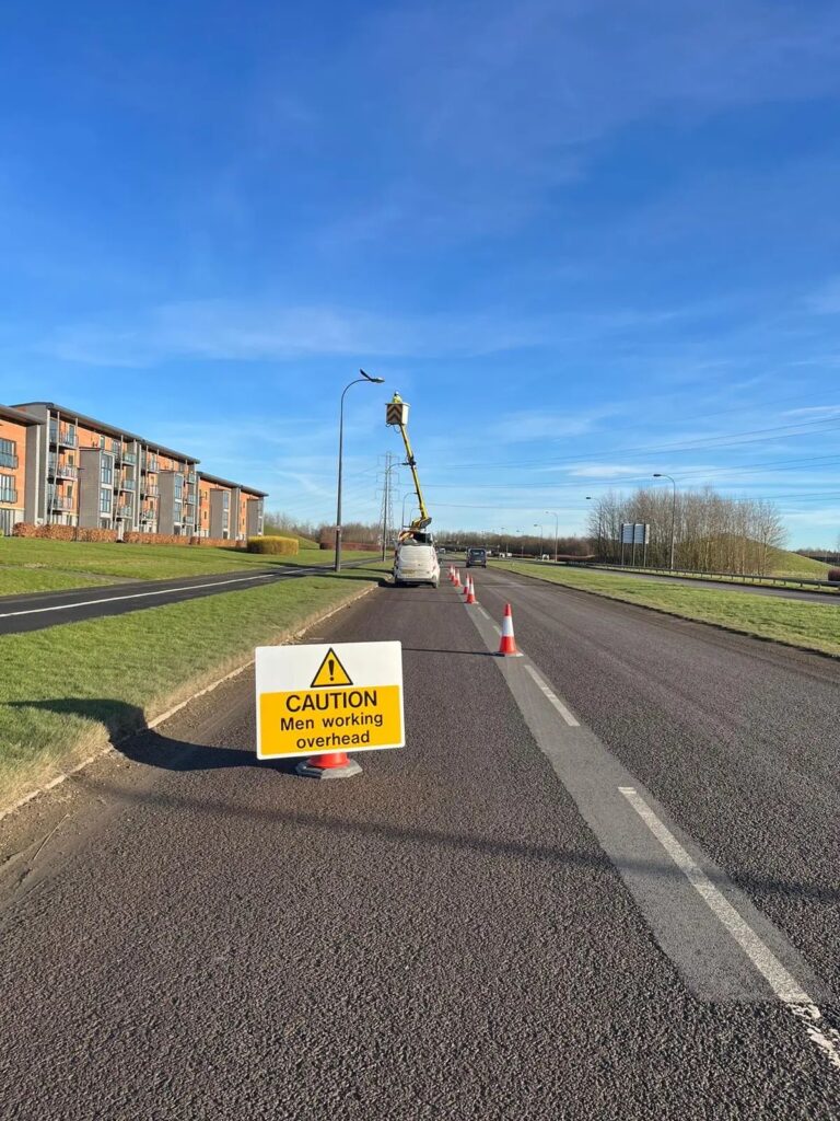 SecureTech access platform working on a lighting column beside a road